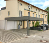 Ein Bild von einem Wintergarten, angebaut an ein Einfamilienhaus mit großzügigem Garten.